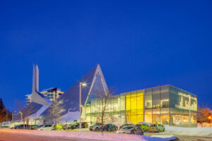 Long-exposure photo showing the side of the library illuminated at dusk, with a parking lot in the foreground.