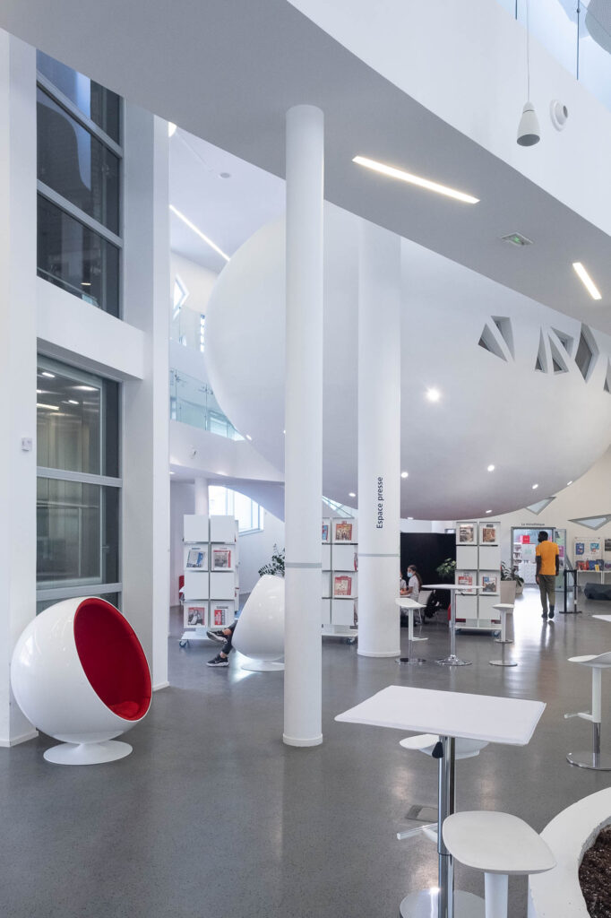 Interior of a contemporary library showing an orb-like room suspended above an atrium.