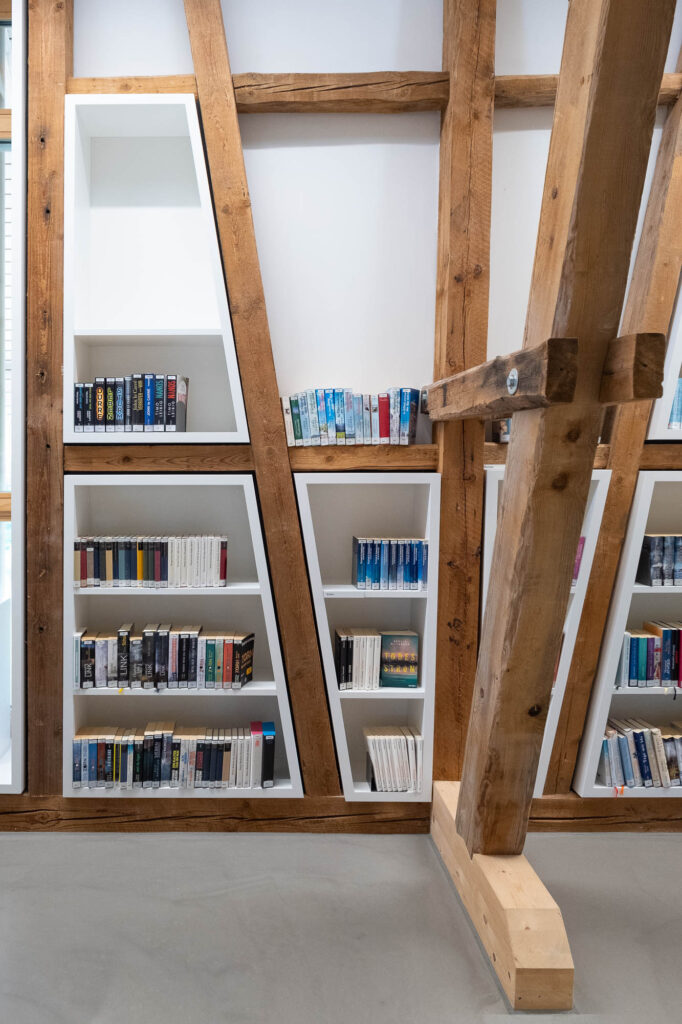 Bookshelves built between slanted timber beams.