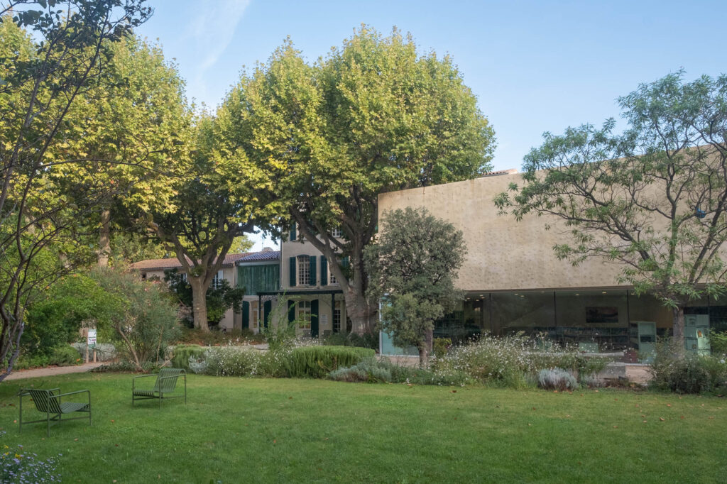 Exterior of a old house converted to a library, with a modern wing to the right. In front is a manicured park with mature trees.