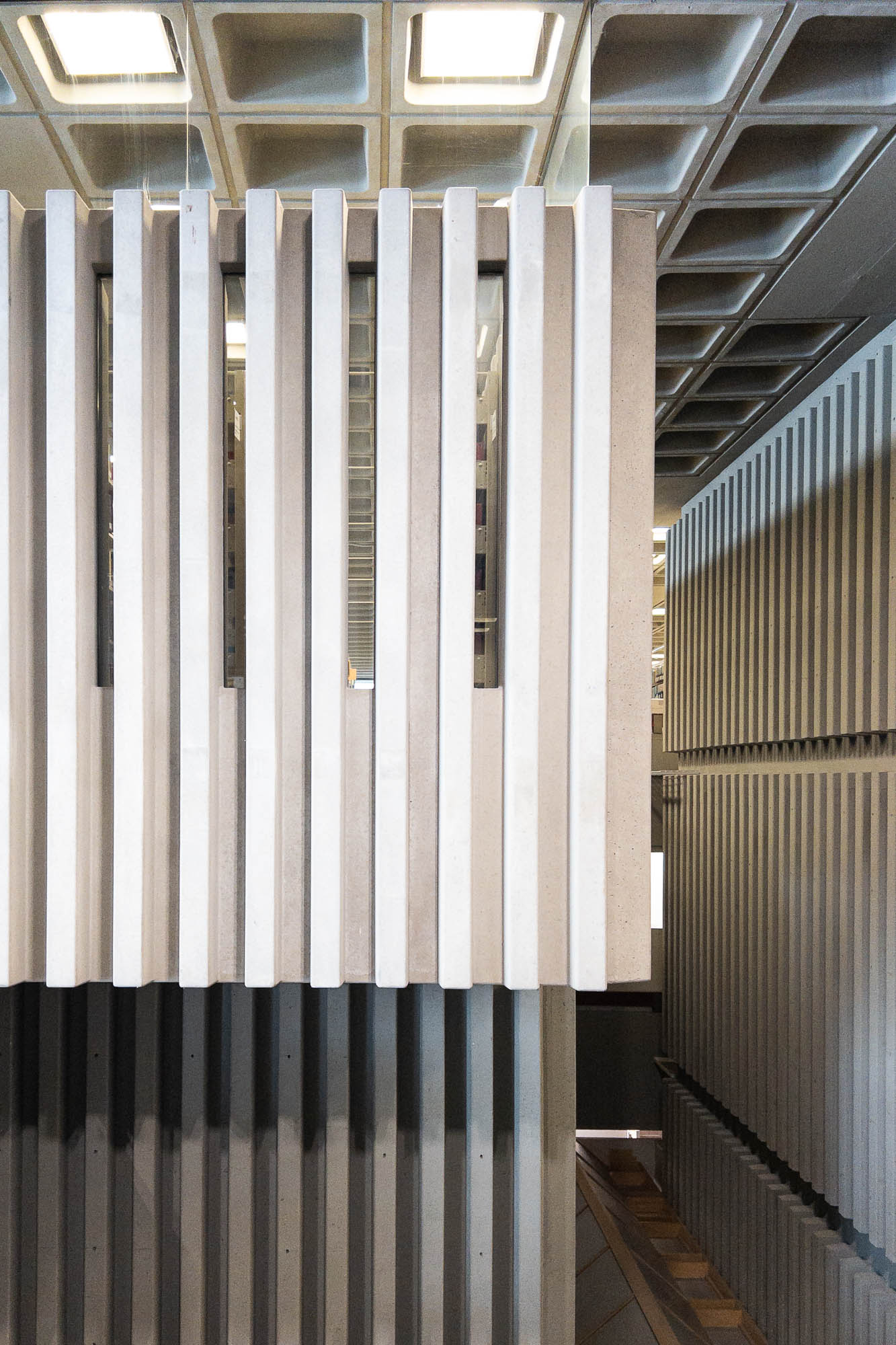Interior of a brutalist library with interior walls detailed in thin vertical concrete fins.