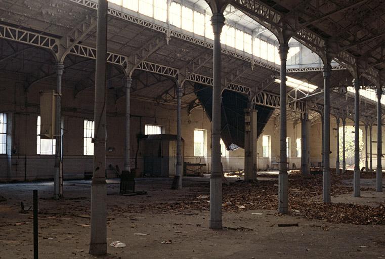 Interior of a decrepit industrial hall with debris on the ground.