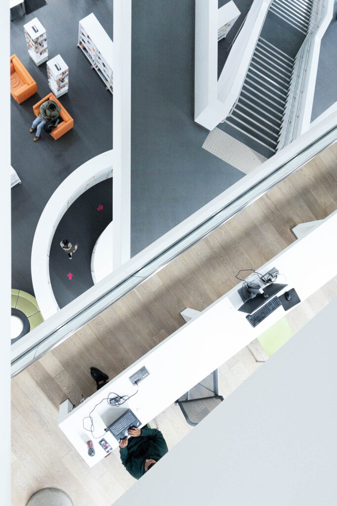 Interior of a contemporary library, looking down an atrium at criss-crossing stairs and corridors.