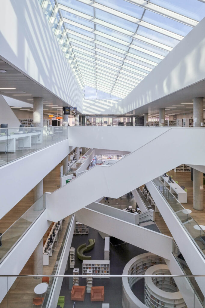 Interior or a contemporary library with stairs criss-crossing a long atrium.