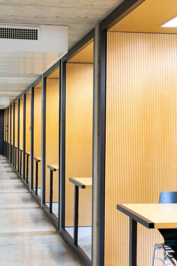 Contemporary library interior, showing a row of square cubicles enclosed by wood lattice panels.