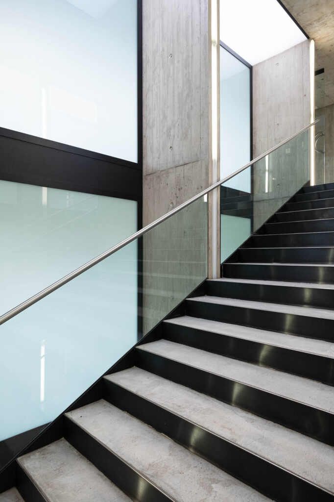 Contemporary library interior, showing a concrete and glass staircase.