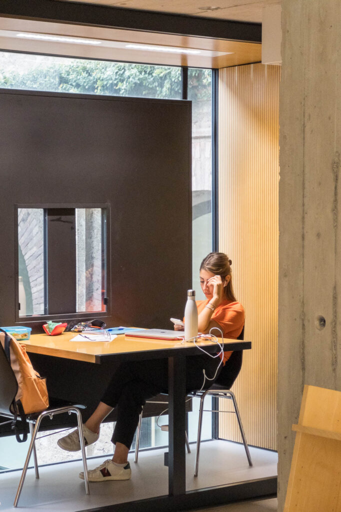 Interior of a contemporary library showing a person sitting in a cubicle.