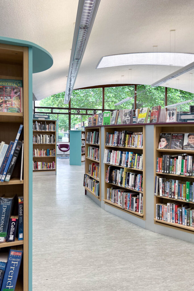 Interior of a modern library, with a gently curving ceiling and a large window at the back.
