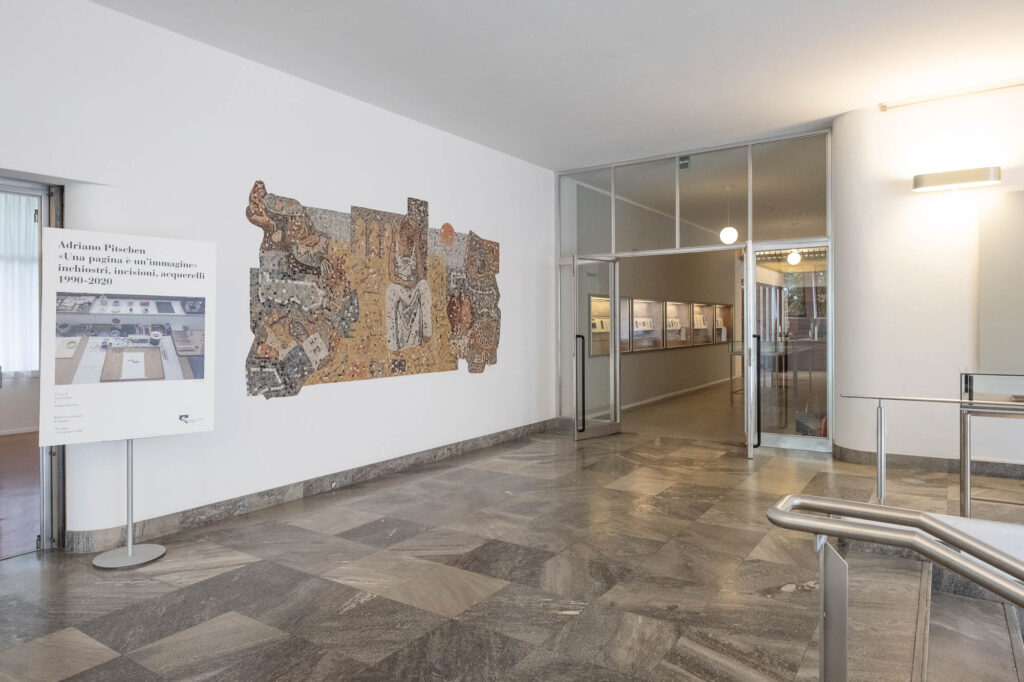 Interior of a modernist library, showing a marble clad landing on top of stairs. To the right is a glazed door leading to the library. A mosaic decorates the wall to the left.