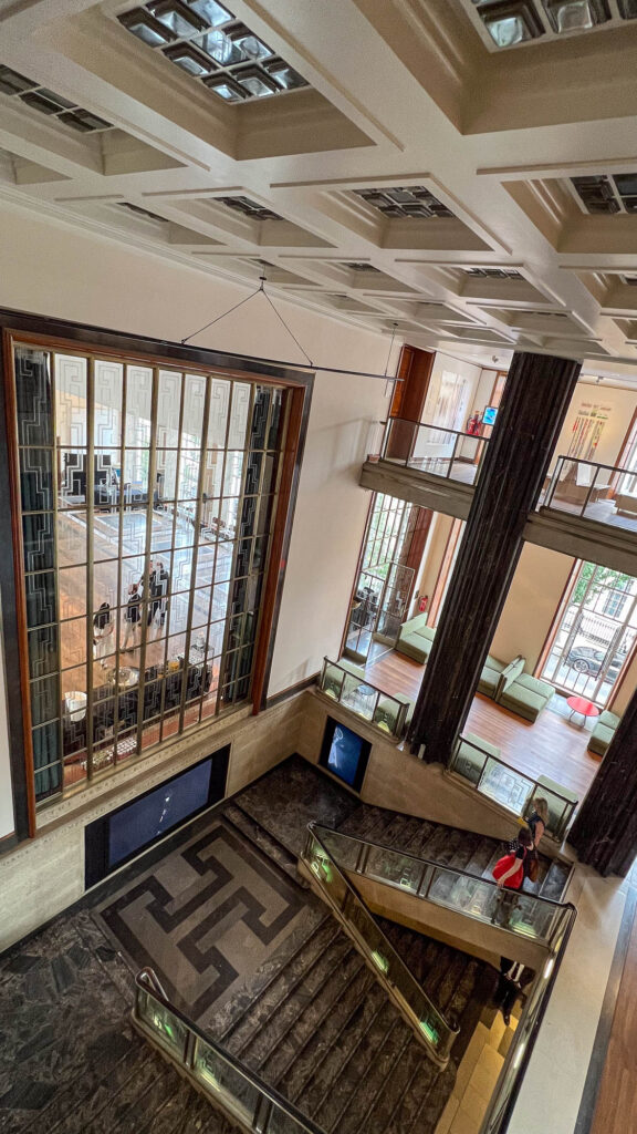 Wide-angle image looking down on a large open staircase in an Art-Deco building.