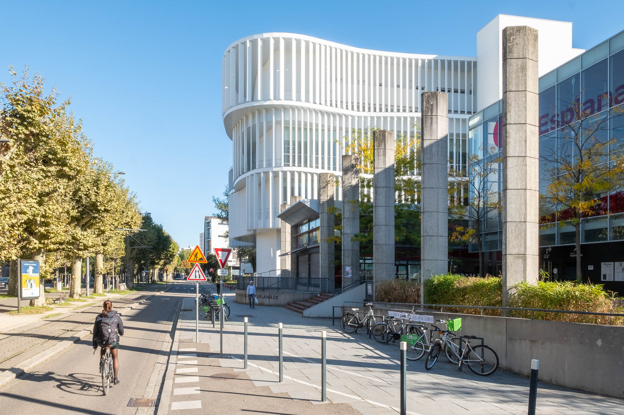 Exterior of a contemporary library, a white curvy building with vertical brise-soleils.