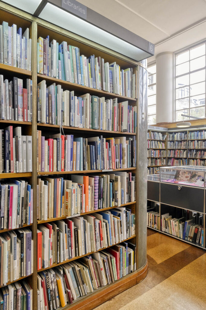 Interior of a library, closeup of a full bookshelf labelled "Libraries" and bearing the number "6".