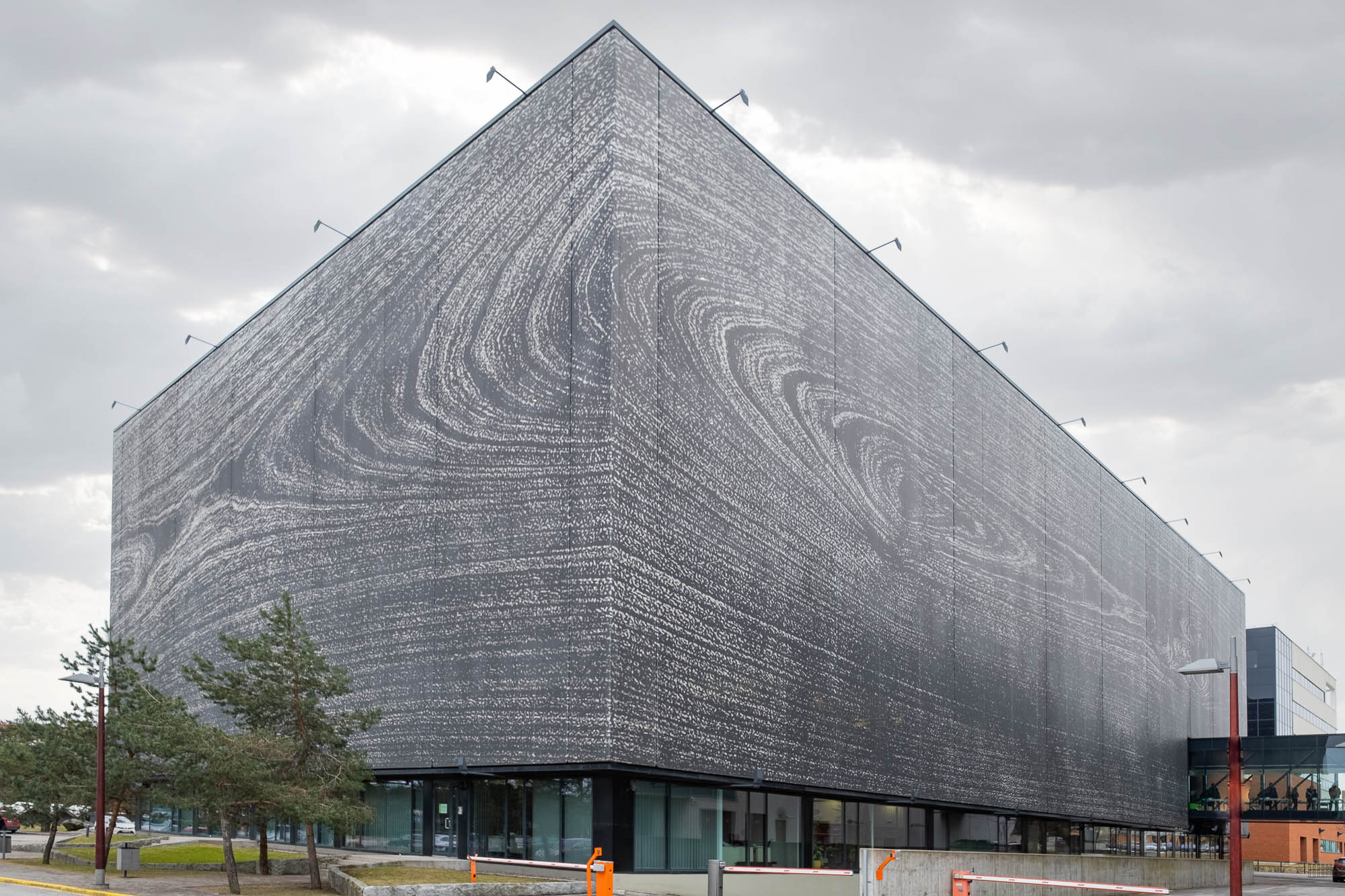 Exterior of a contemporary library. I is a rectangular building covered with a fabric skin printed with tree rings so as to resemble a large piece of wood. The translucent outer fabric hides the inner windows.