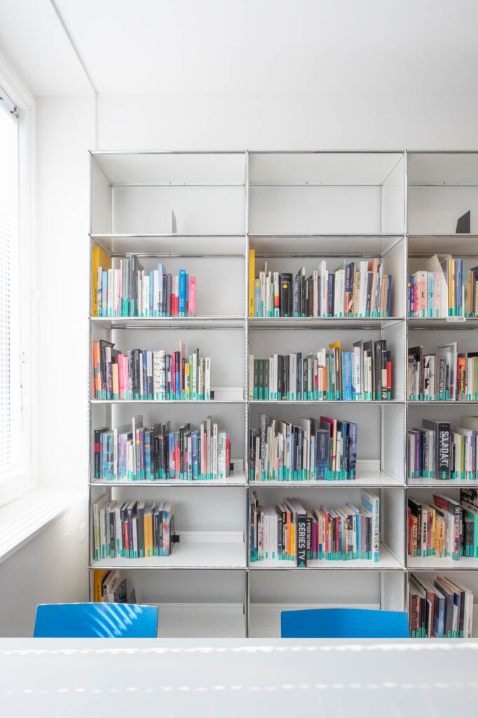 Interior of a library showing a white metal bookshelf against a wall.