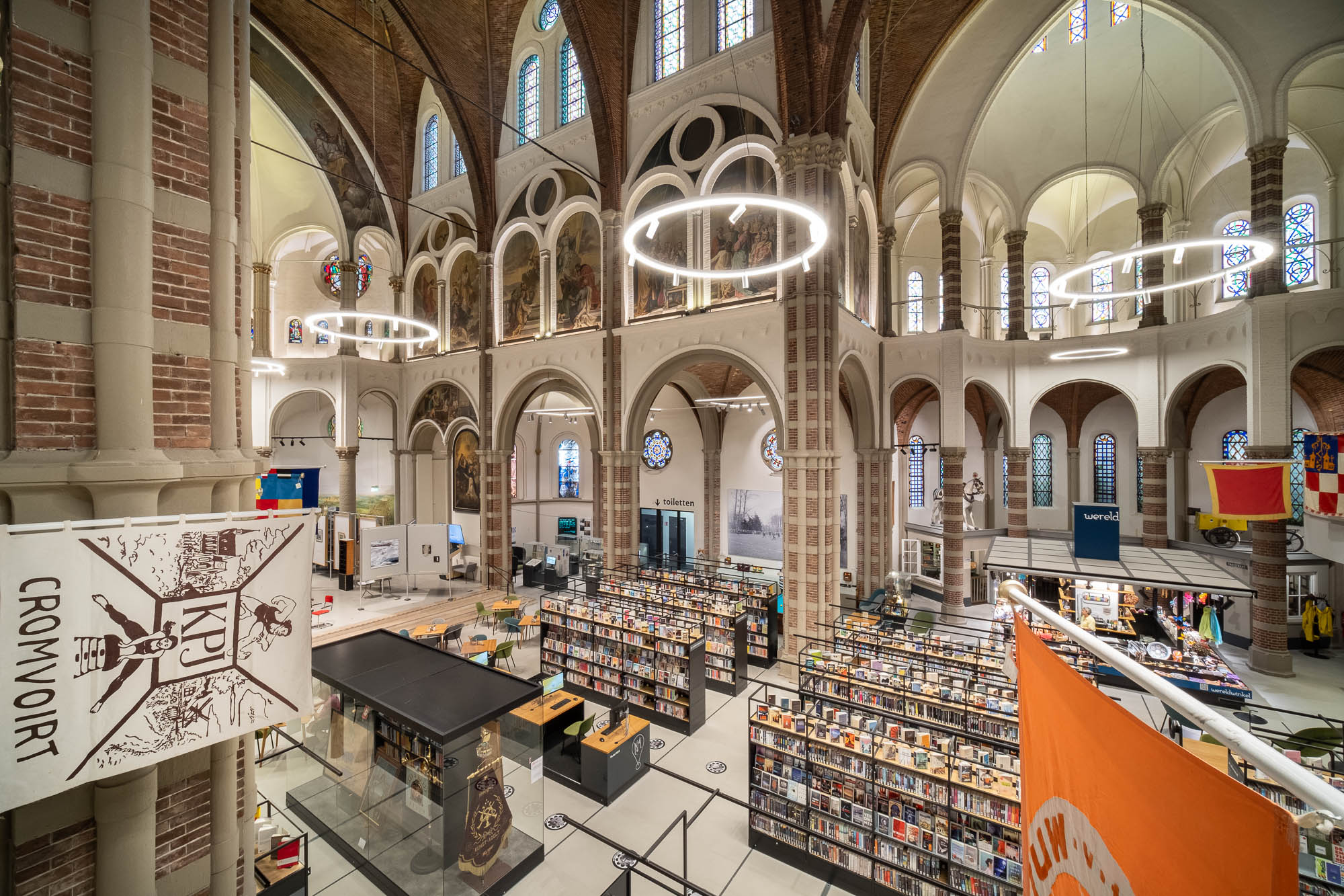 Interior of a brick church converted to a library with rows of contemporary bookshelves contrasting with the church interior.