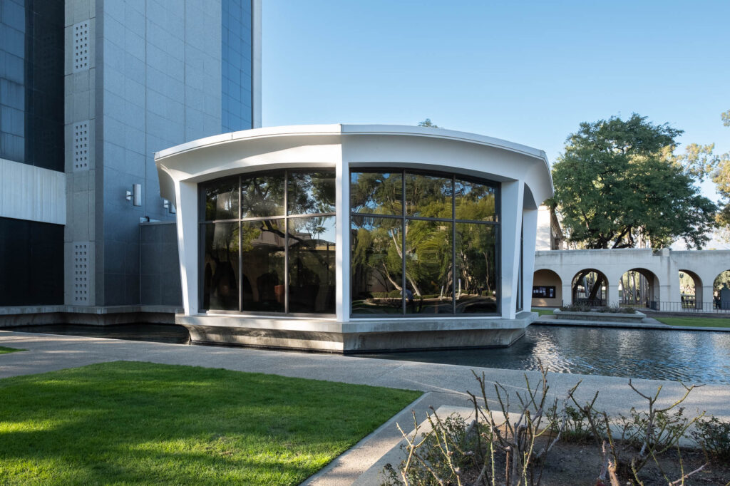 Exterior of a modernist octagonal pavilion overlooking a reflecting pool.