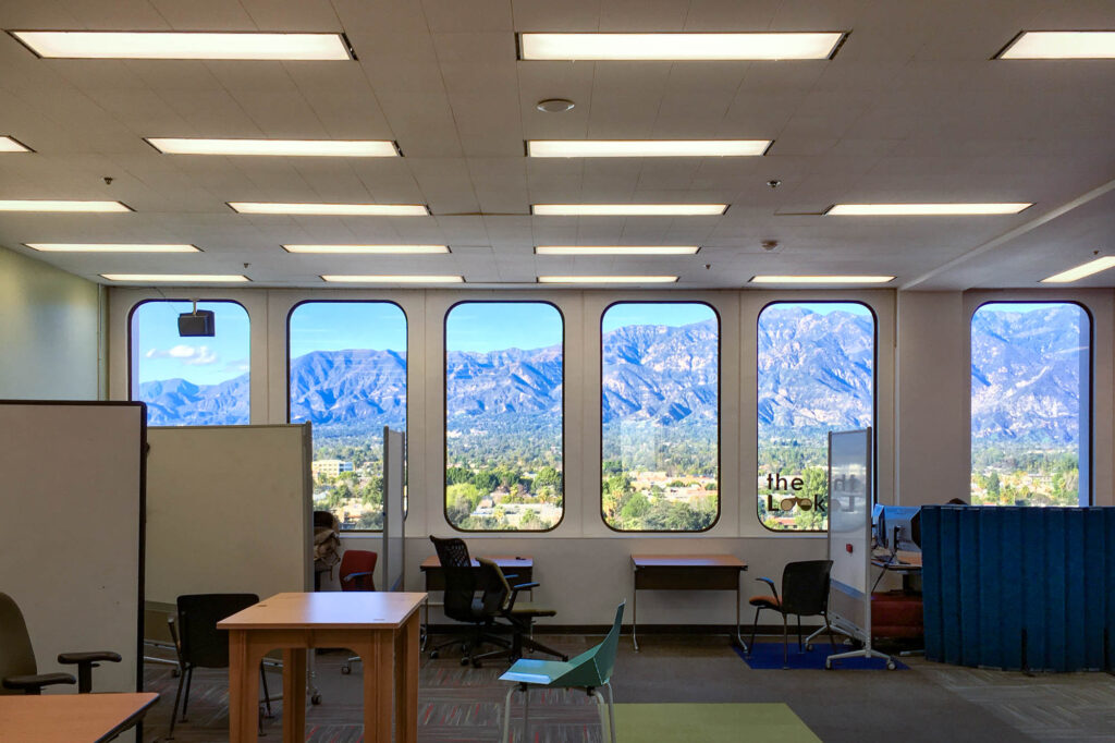 Inside of a building with rounded rectangular windows. The view through the windows is of a mountain range.