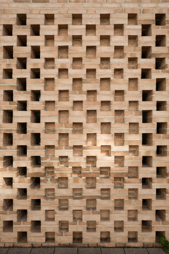 Close up of a brick wall, with bricks arranged in an alternating fashion to create regular openings between blocks.