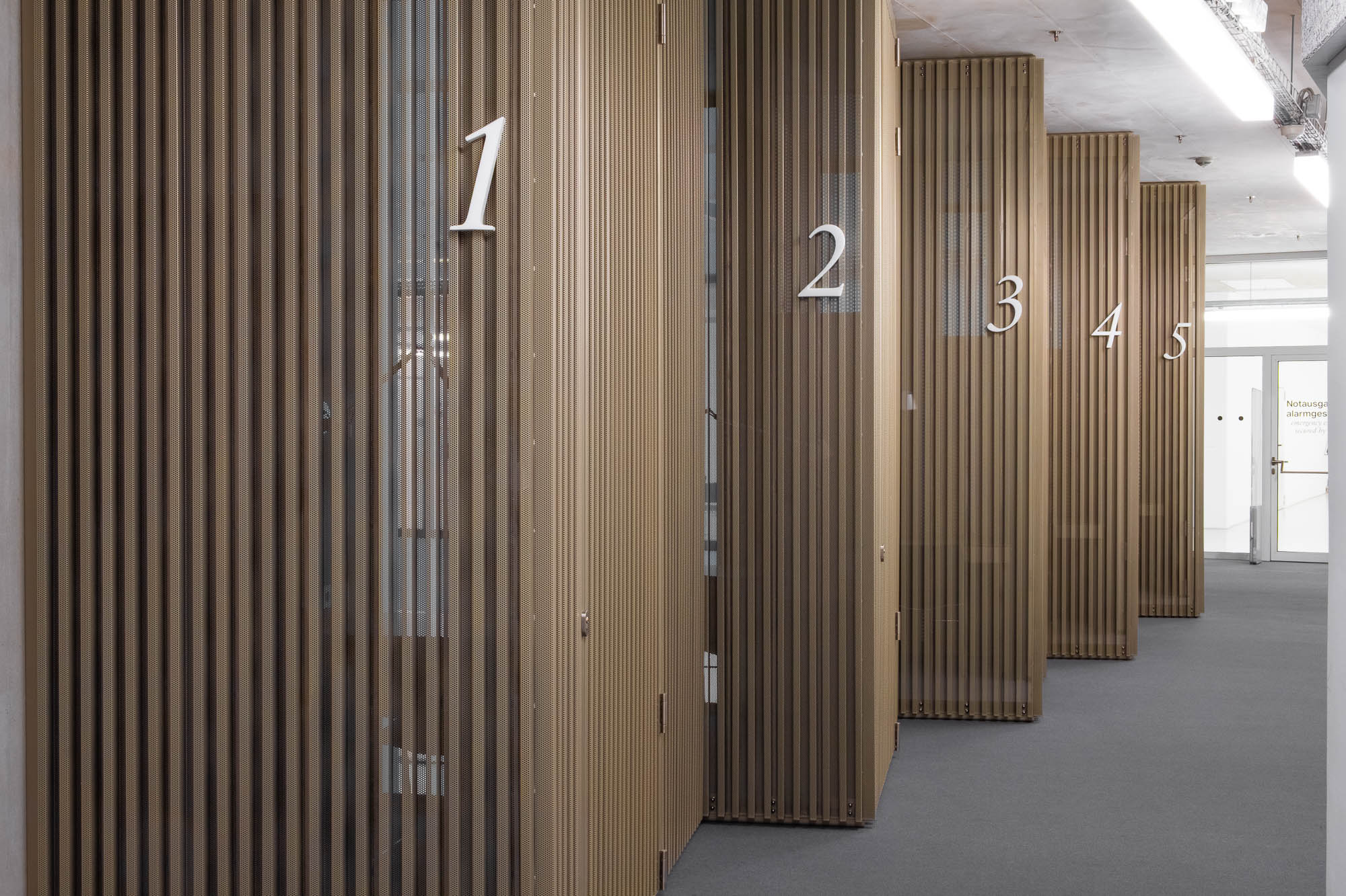 A line of study booths numbered 1 to 5. The walls are a copper-coloured lattice of perforated steel.