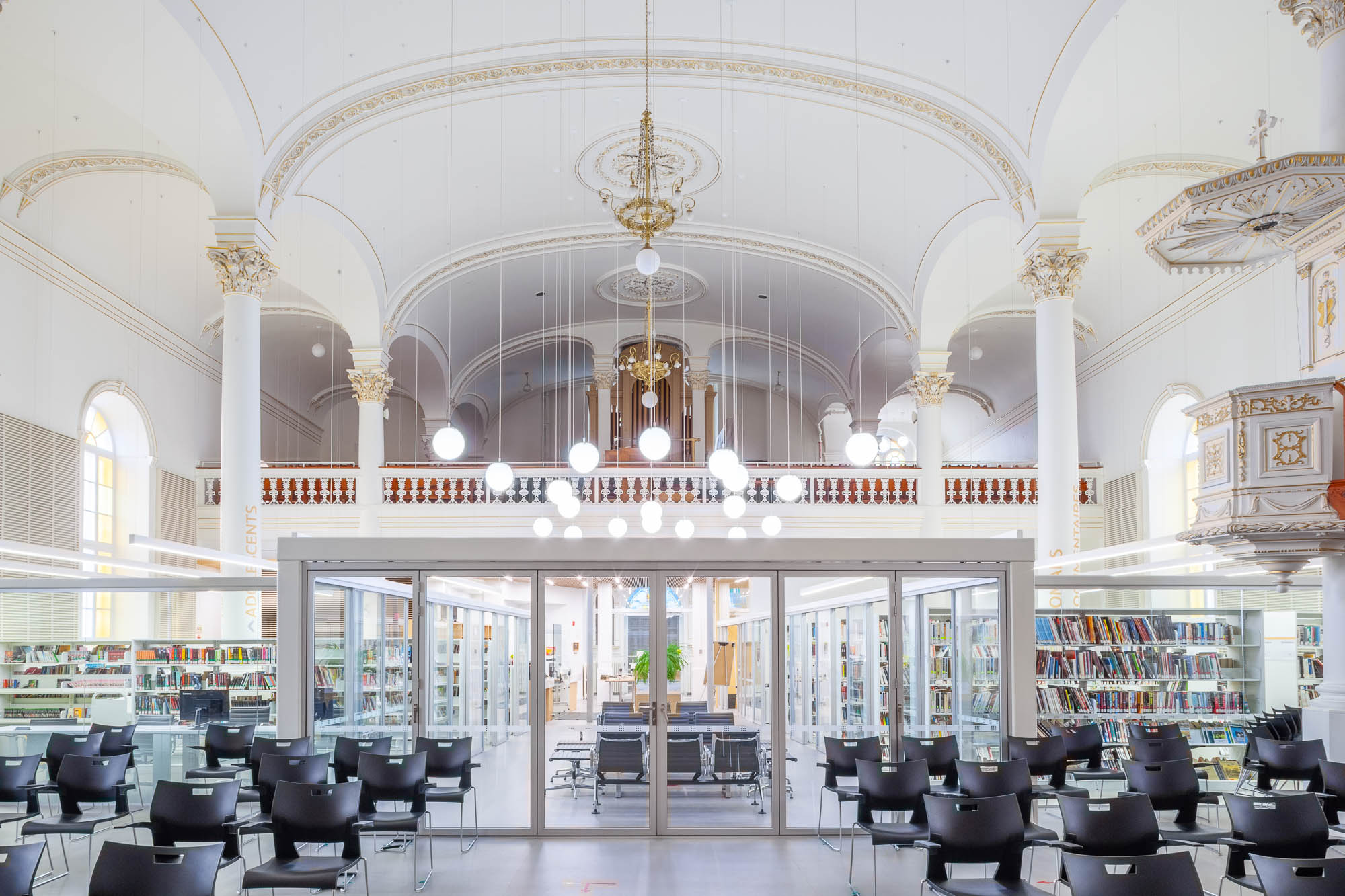 Interior of a church converted to a library. A glass enclosure containing the library is at the back, only occupying part of the church, which can be seen around the library.